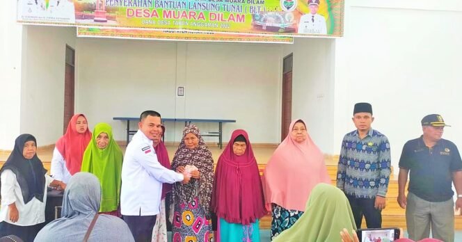 
FOTO : Kepala Desa Muara Dilam Zulfikar SHi menyerahkan BLT-DD Tahap VI kepada 140 KPM, Rabu (8/6/202)